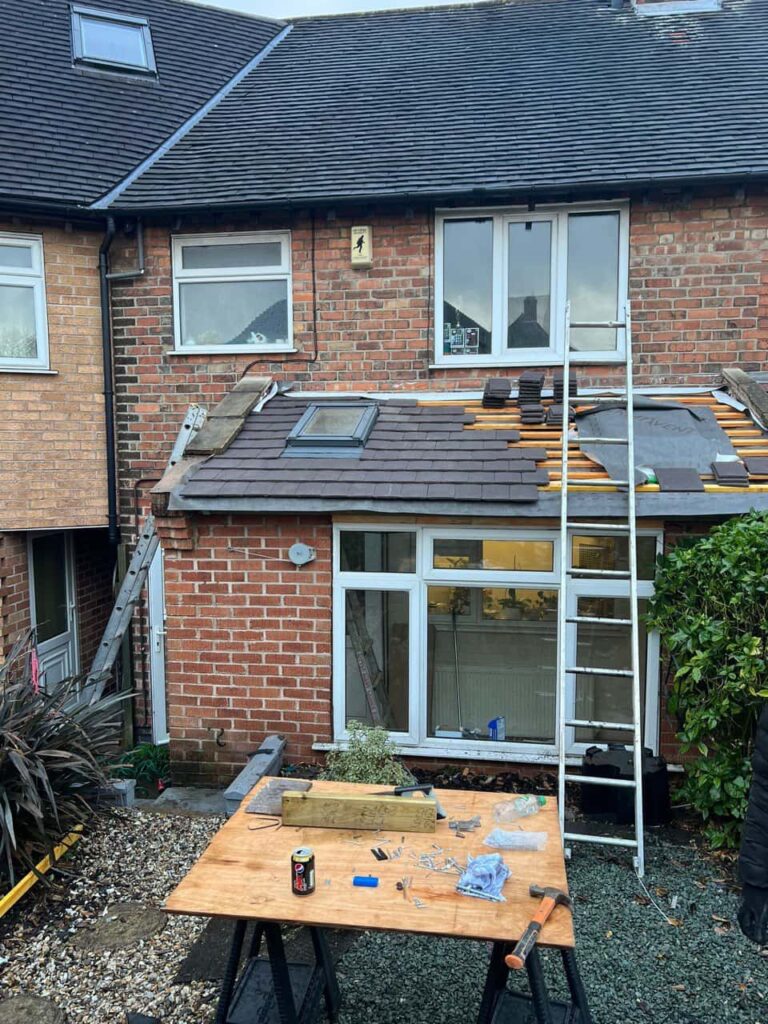 This is a photo of a roof extension that is having new roof tiles installed. This is a photo taken from the roof ridge looking down a tiled pitched roof on to a flat roof. Works carried out by Great Barr Roofing Repairs